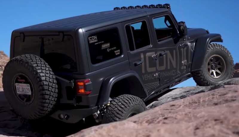 A jeep navigates a steep, rocky hill, showcasing its off-road capabilities in a rugged landscape